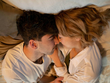 "Couple relaxing together in bed, embracing intimacy and connection – promoting sexual wellness for busy professionals"